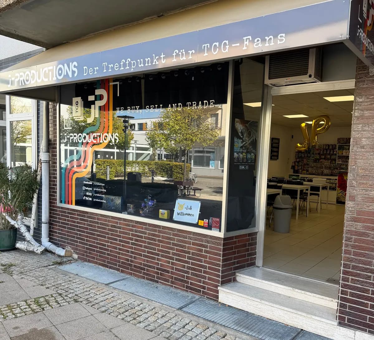 J-Productions von außen mit Schaufenster, Unternehmenslogo und geöffnetem Store-Eingang
